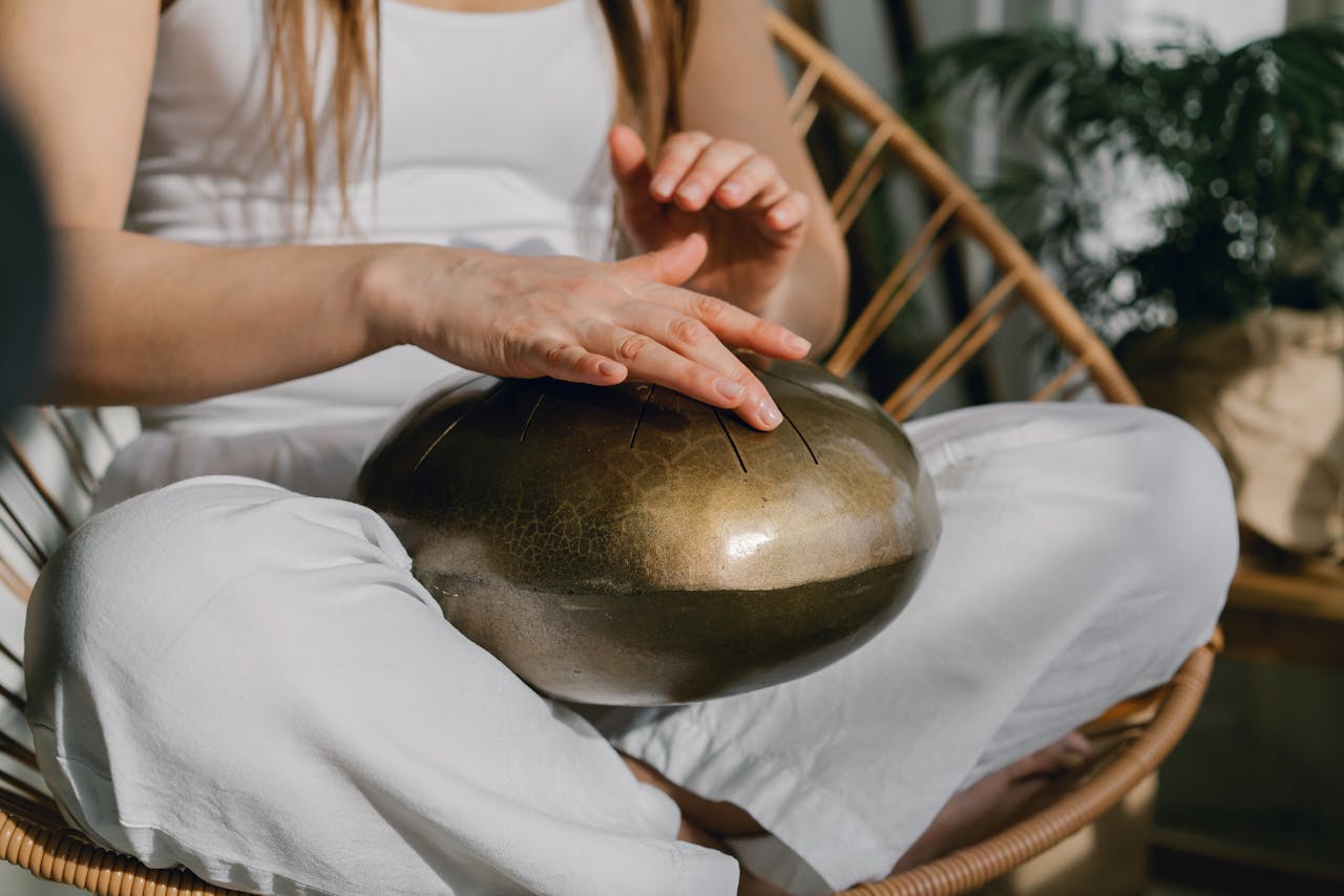 The Art of Drawing Readers In: Your attractive post title goes here A person sits meditating, playing a handpan for relaxation and mindfulness.